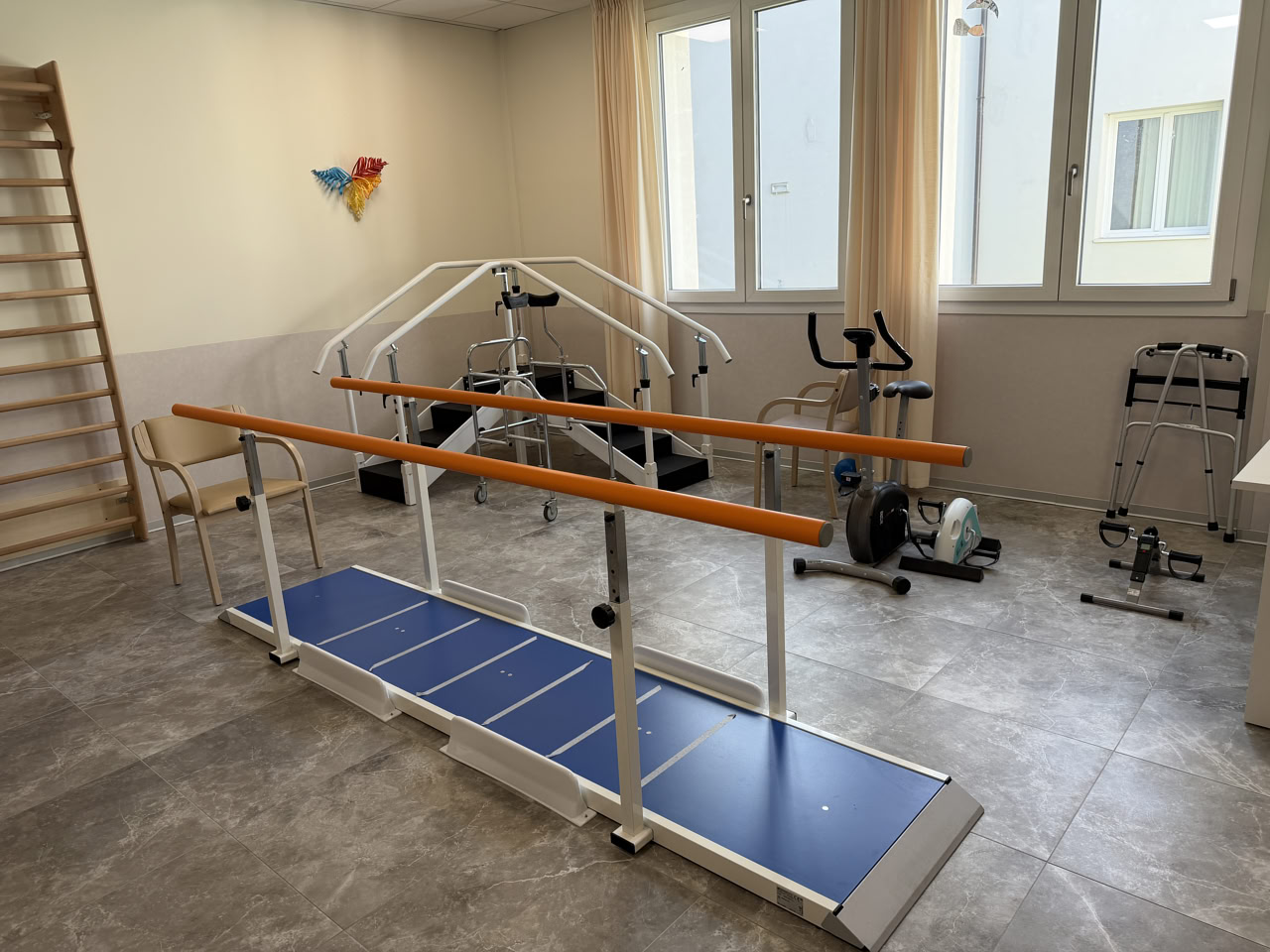 Sala di fisioterapia con parallele, cyclette, deambulatori e attrezzature per la riabilitazione
