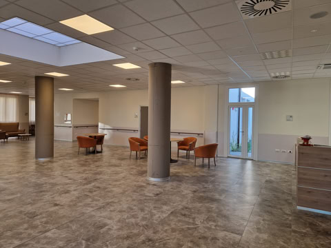 Sala comune con poltrone, colonne in cemento e accesso al giardino