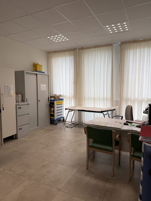 Studio medico con armadi, scrivania e lettino