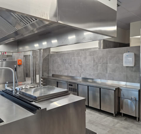 Cucina professionale con cappe aspiranti e attrezzature inox