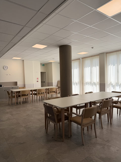 Sala da pranzo con tavoli rettangolari, sedie e colonna in cemento