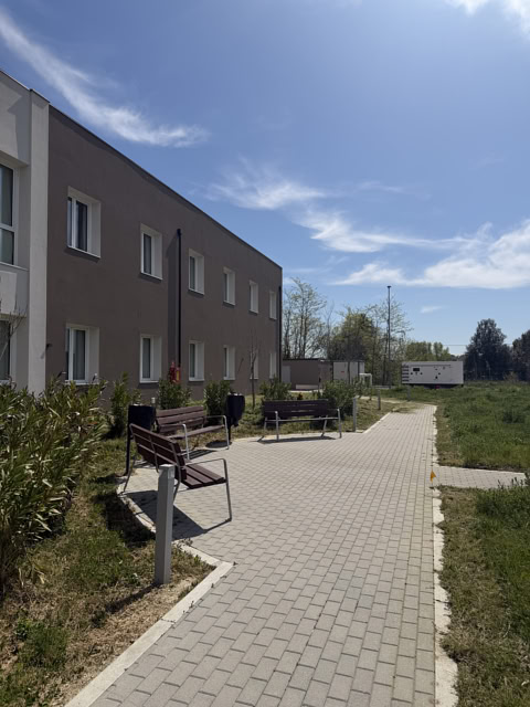 Vista esterna con vialetto pedonale, panchine ed edificio residenziale